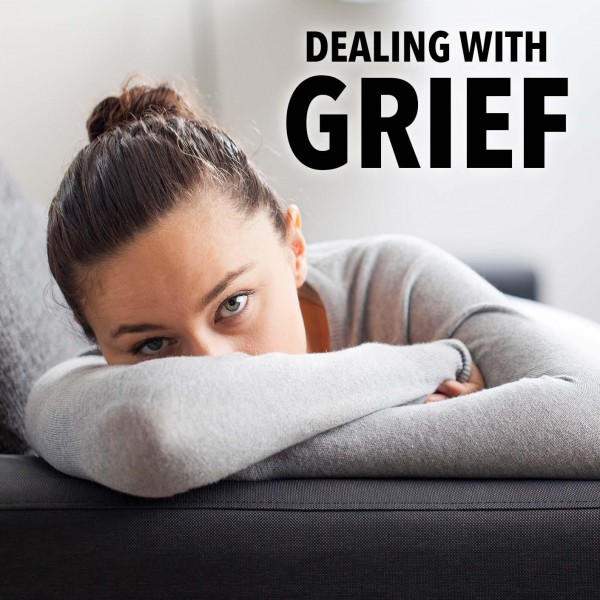 A woman rests her head on her arms while lying on a sofa, looking ahead with a serious expression. Large text above her reads, "Dealing with Grief.